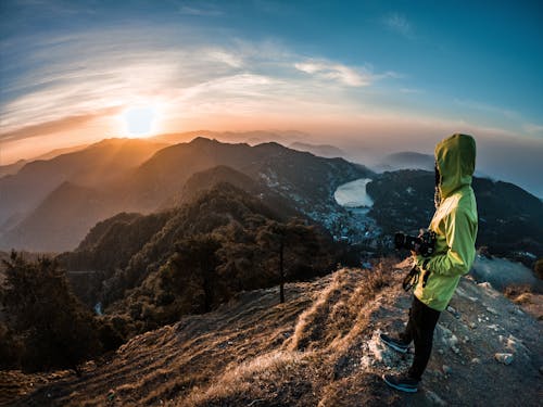 Person In Green Hoodie Standing Looking At Sunset