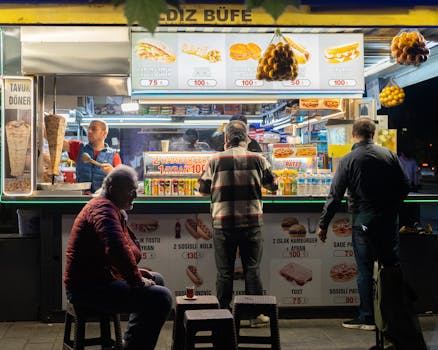 Lively street food stand in İstanbul at night, serving variety of snacks.