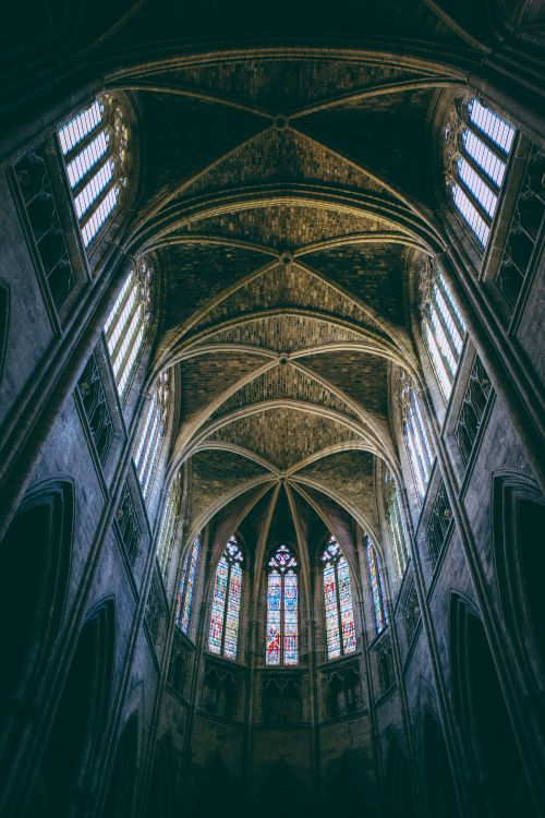 Free Interior view of a Gothic cathedral showcasing intricate arches and colorful stained glass windows. Stock Photo