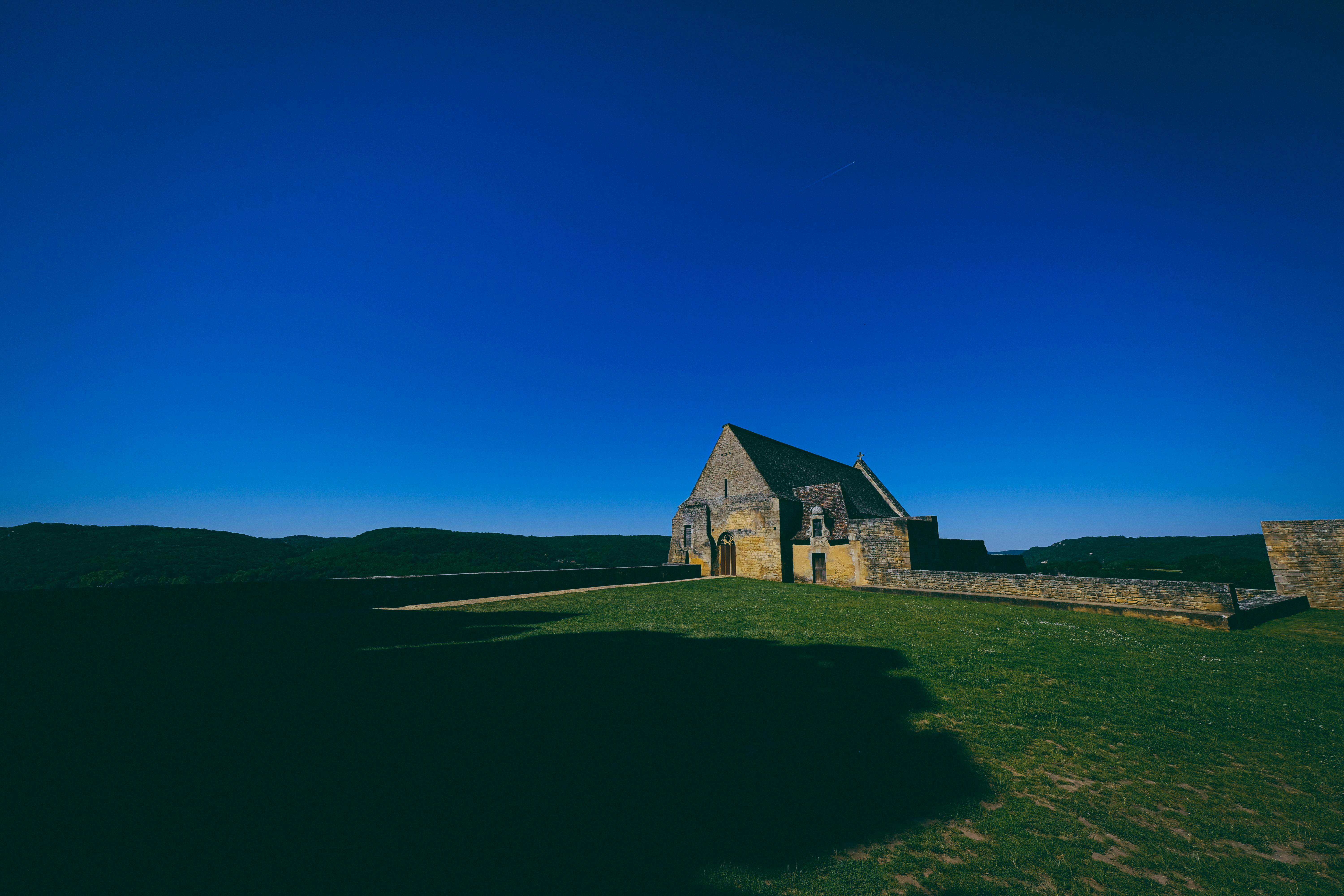 这座风景如画的石头房屋坐落在明亮的蓝天之下，置身于乡村景观之中，非常适合旅行和自然爱好者