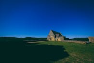 这座风景如画的石头房屋坐落在明亮的蓝天之下，置身于乡村景观之中，非常适合旅行和自然爱好者