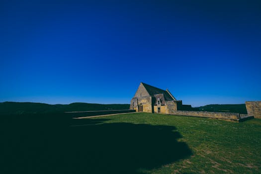 这座风景如画的石头房屋坐落在明亮的蓝天之下，置身于乡村景观之中，非常适合旅行和自然爱好者