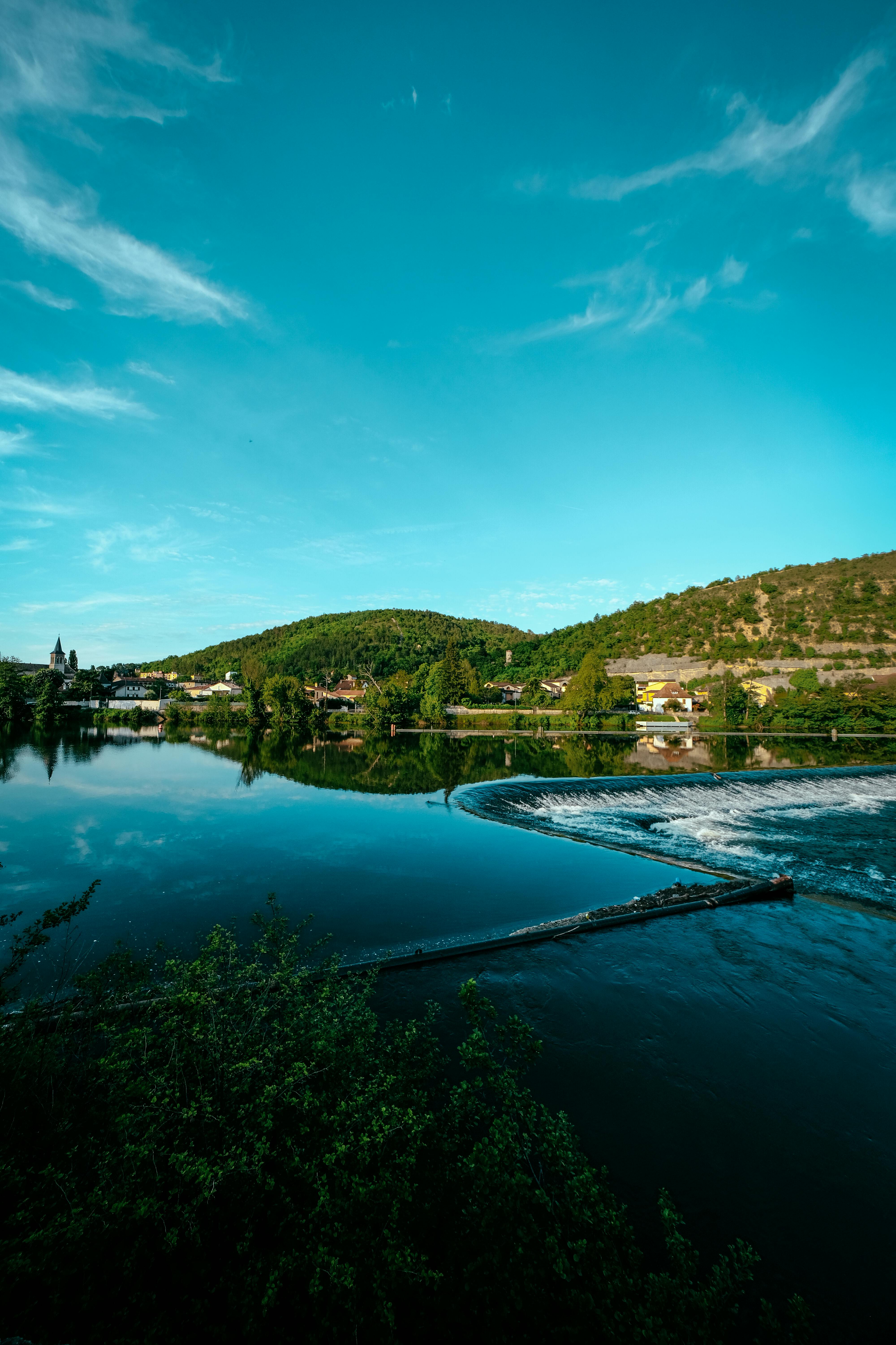 湖畔村庄绿树成荫，天空蔚蓝，景色宁静