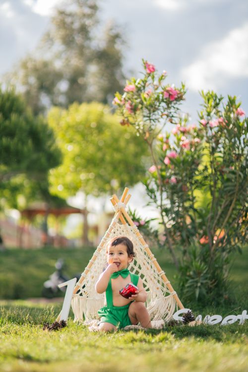 Free Cute child in green outfit sitting by a tent in a park, celebrating his first birthday. Stock Photo