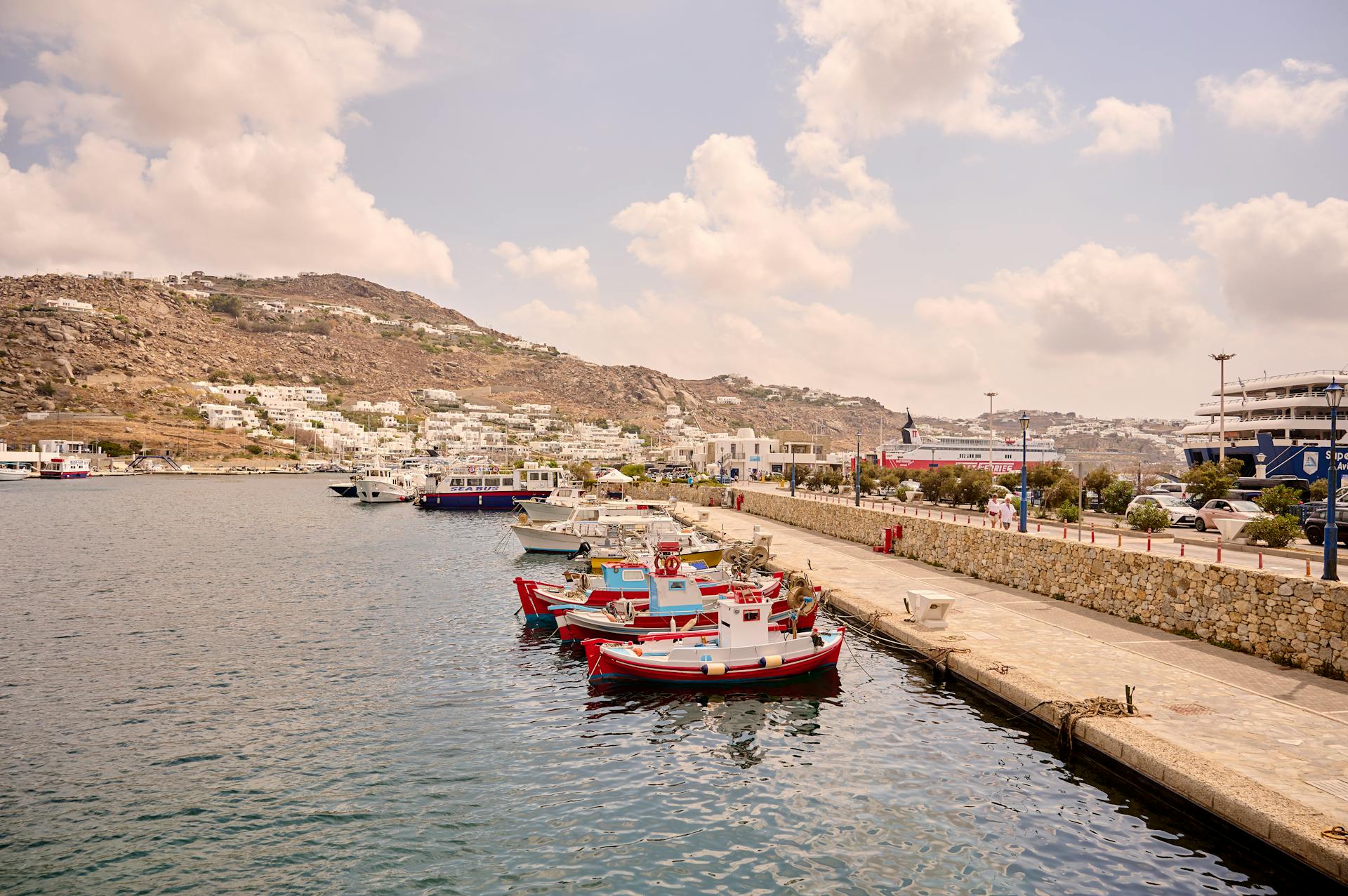 Quaint fishing boats docked at the picturesque Mykonos harbor under a bright sky.