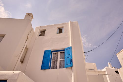 A white building with blue shutters and a blue window