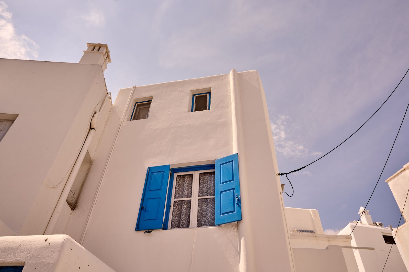 Whitewashed house with blue shutters under a clear sky