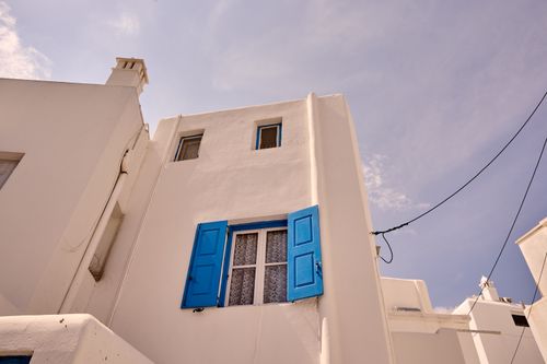Free Detailed view of a Greek-style white house with vibrant blue shutters, under a clear sky. Stock Photo