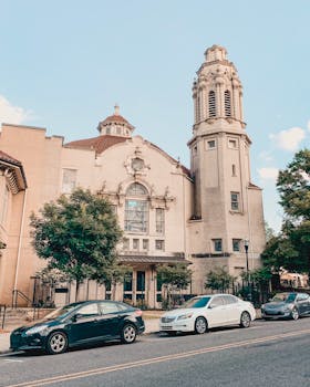 在阳光明媚的城市街道上，一座美丽的历史悠久的教堂矗立着，它有一座突出的塔楼
