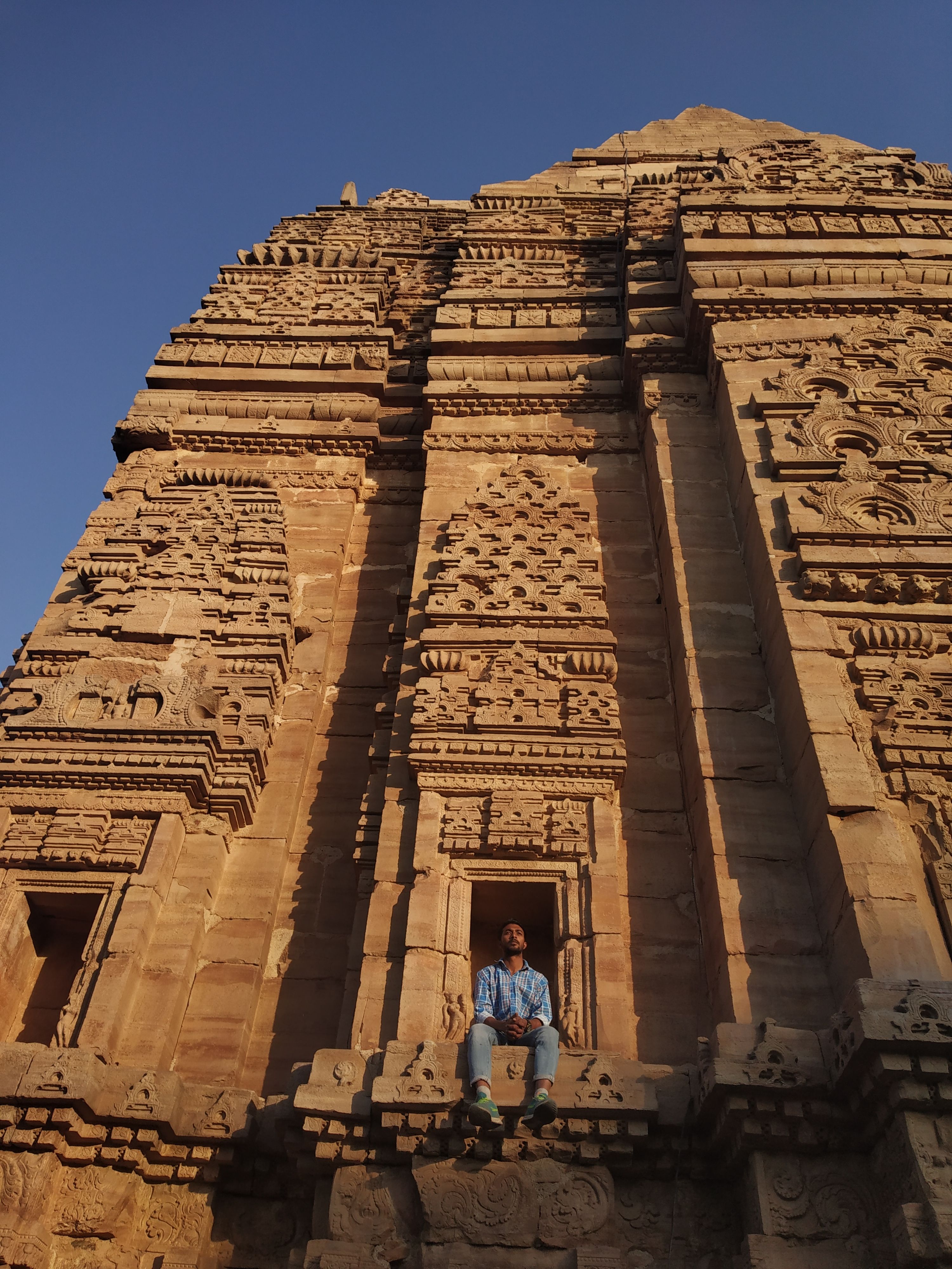 A mesmerizing view of a Hindu temple at Gwalior Fort with a person sitting amidst intricate carvings.