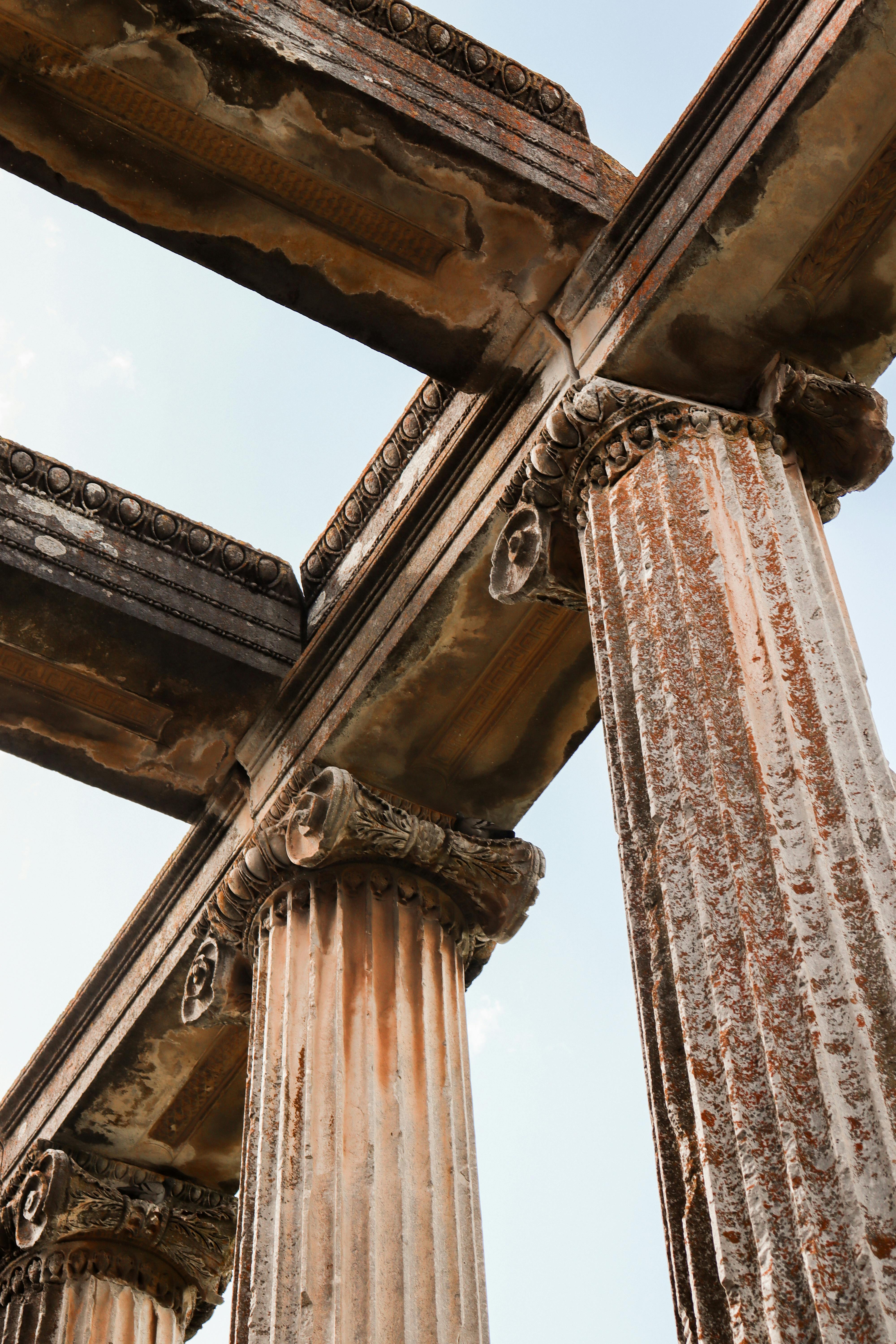 Low angle view of ancient Greek ruins featuring Corinthian columns against a clear sky.