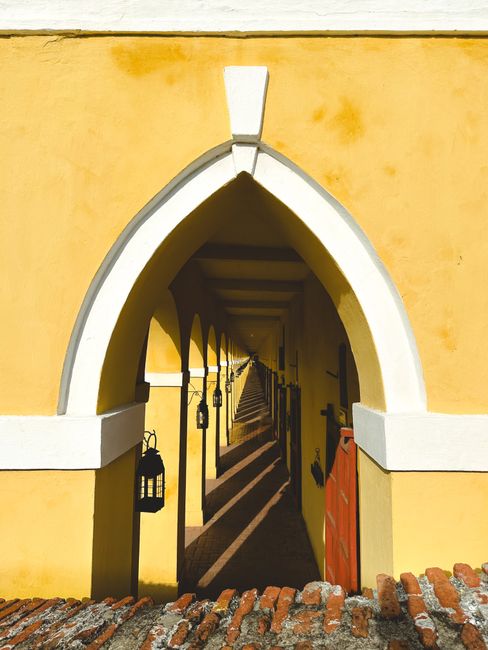 Fotomural Explora la asombrosa perspectiva infinita de un corredor arqueado amarillo con sombras y faroles.