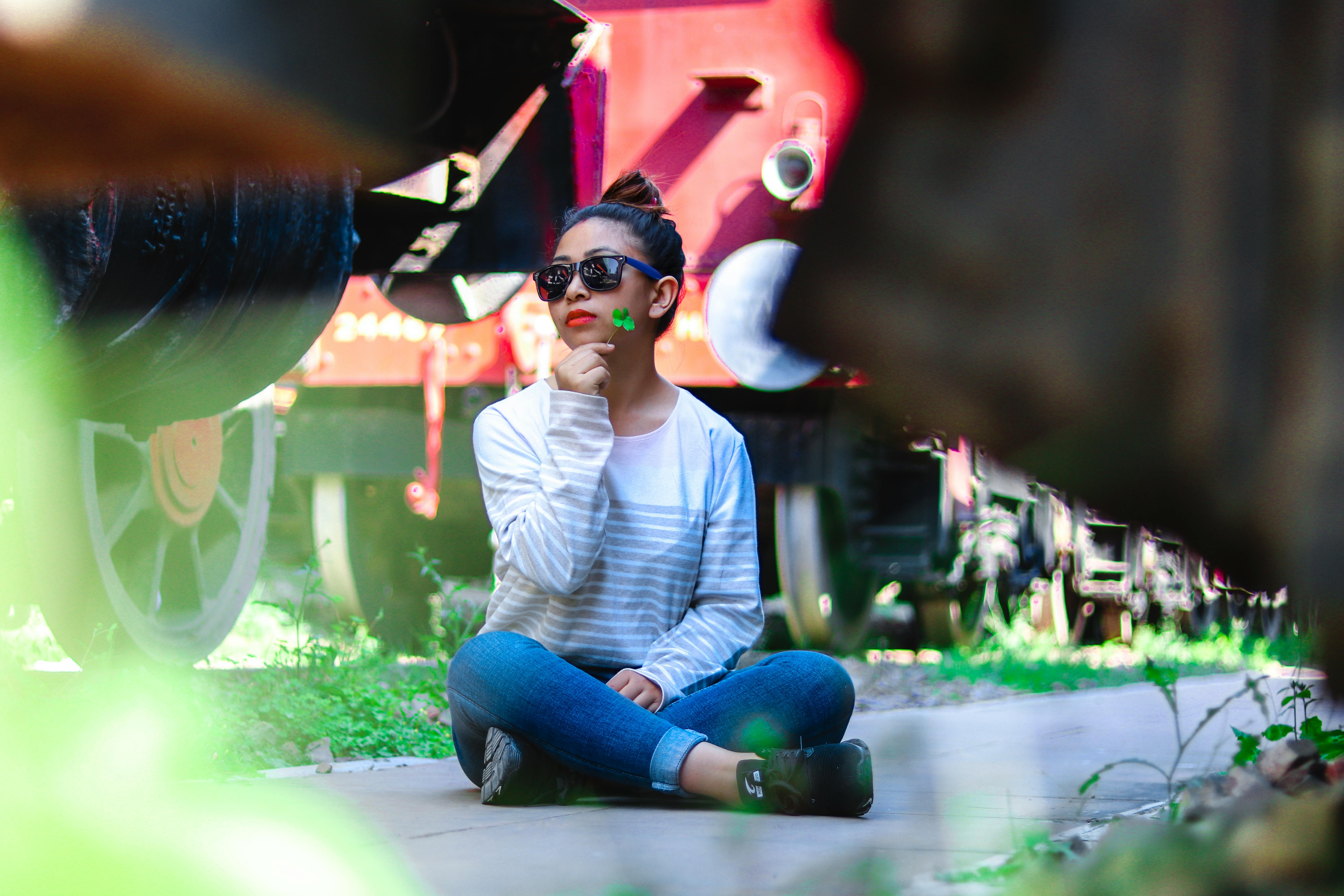 白天，一位穿着休闲装的年轻女子在老式火车旁若有所思地摆着姿势