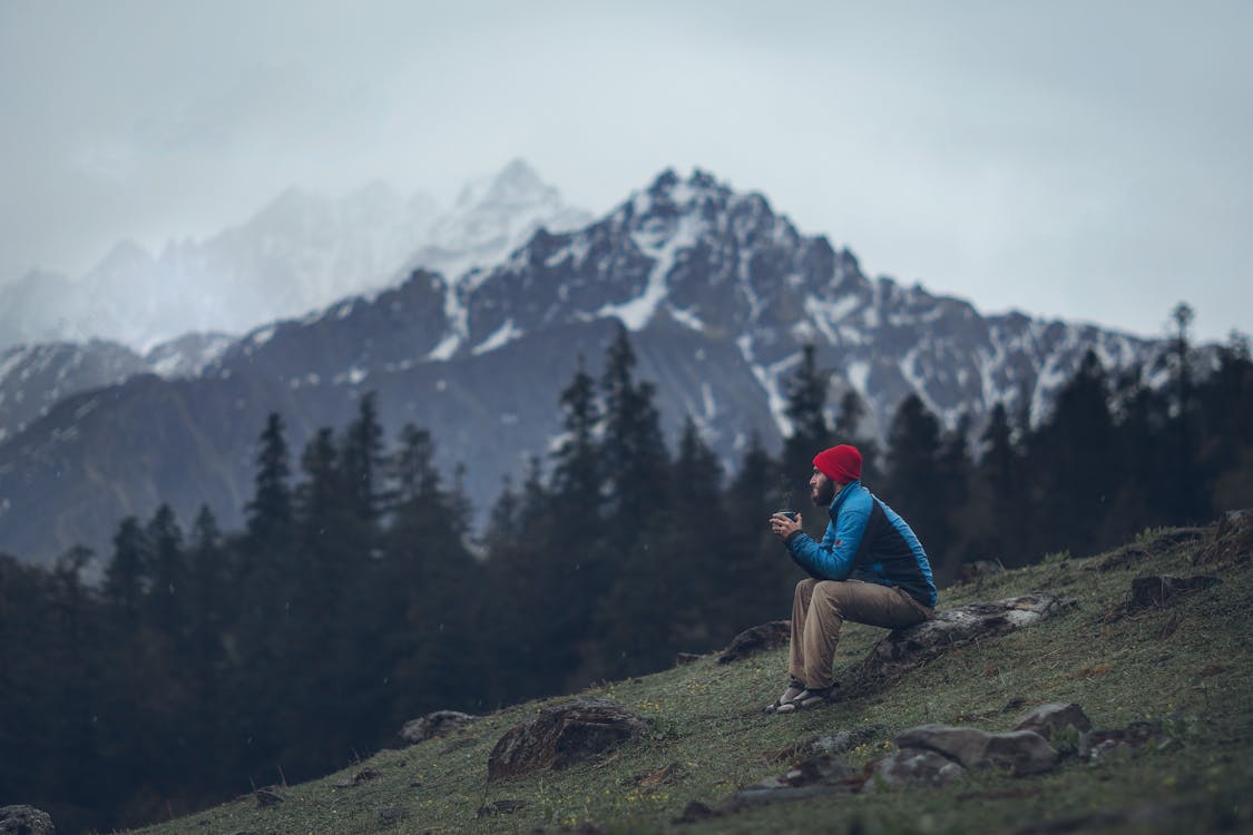 Photo of Man Sitting on Rock