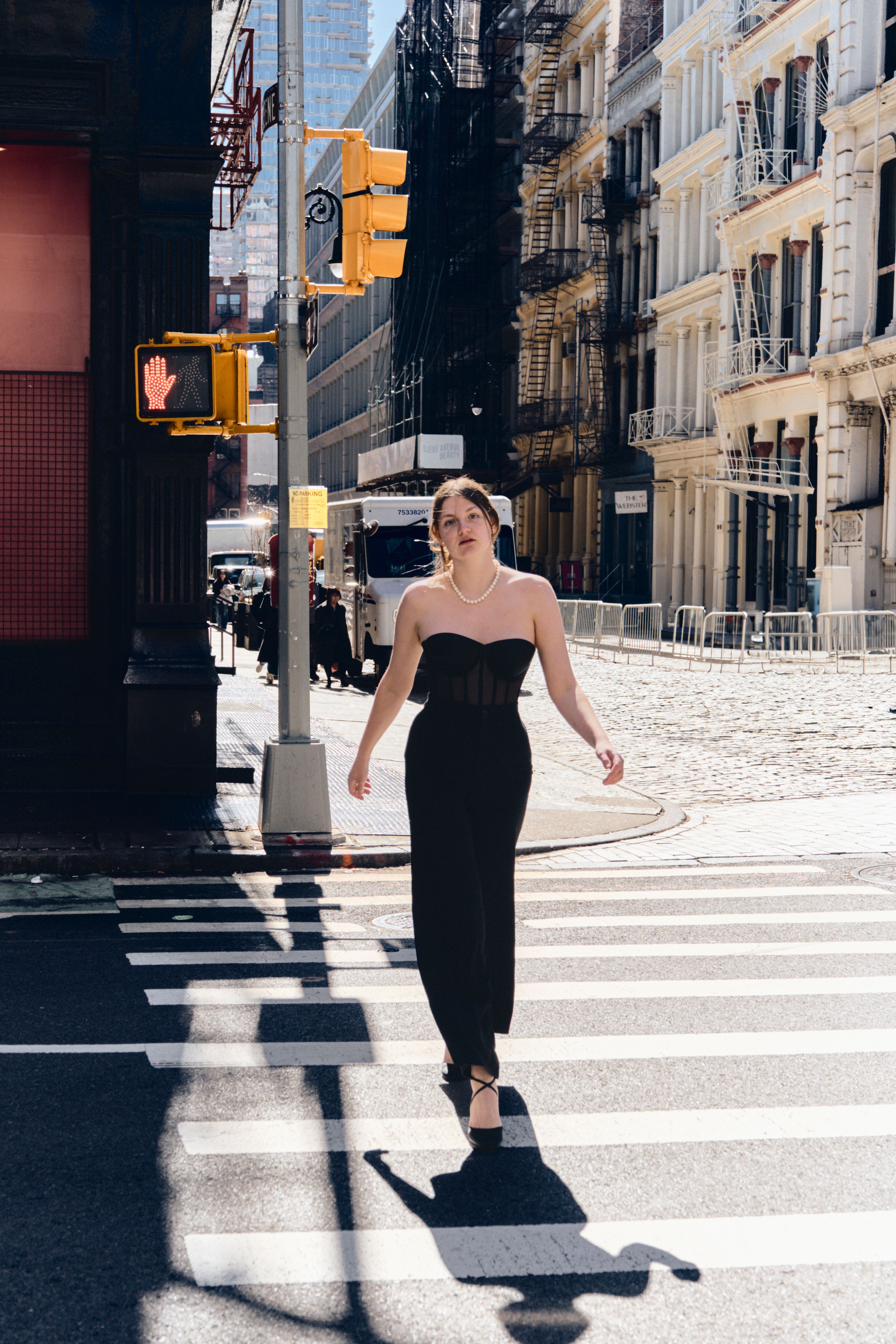 A Young Woman in a Black Dress Walking across the Street · Free Stock Photo