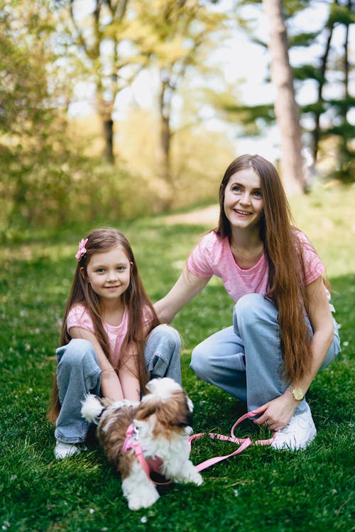 A woman and her daughter are posing for a photo with their dog