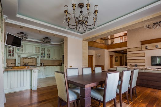 Spacious dining area with a classic chandelier and modern kitchen design.