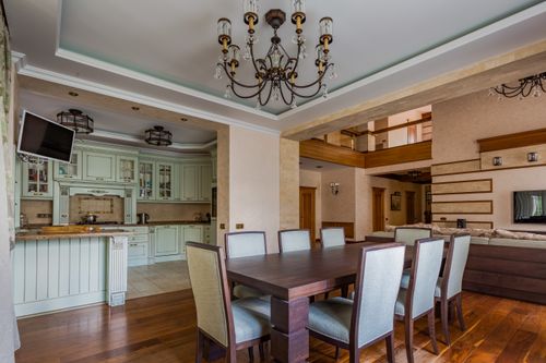 Free Spacious dining area with a classic chandelier and modern kitchen design. Stock Photo