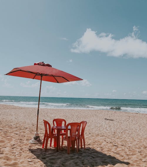 空的紅色桌子和椅子在海灘上的傘的選擇性聚焦照片
