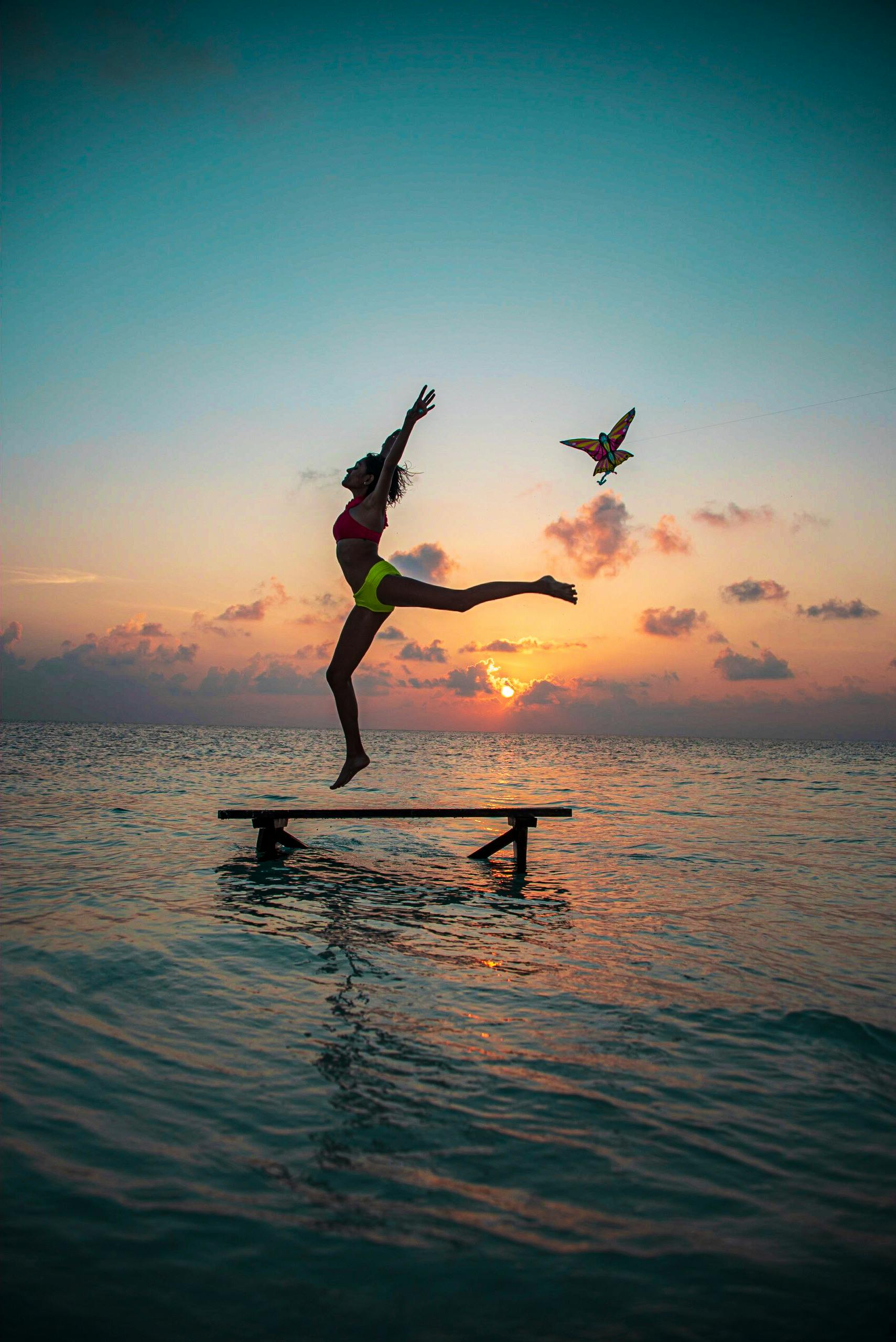 马尔代夫一个充满活力的日落时分，一个人的剪影跳上海滩码头