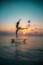马尔代夫一个充满活力的日落时分，一个人的剪影跳上海滩码头