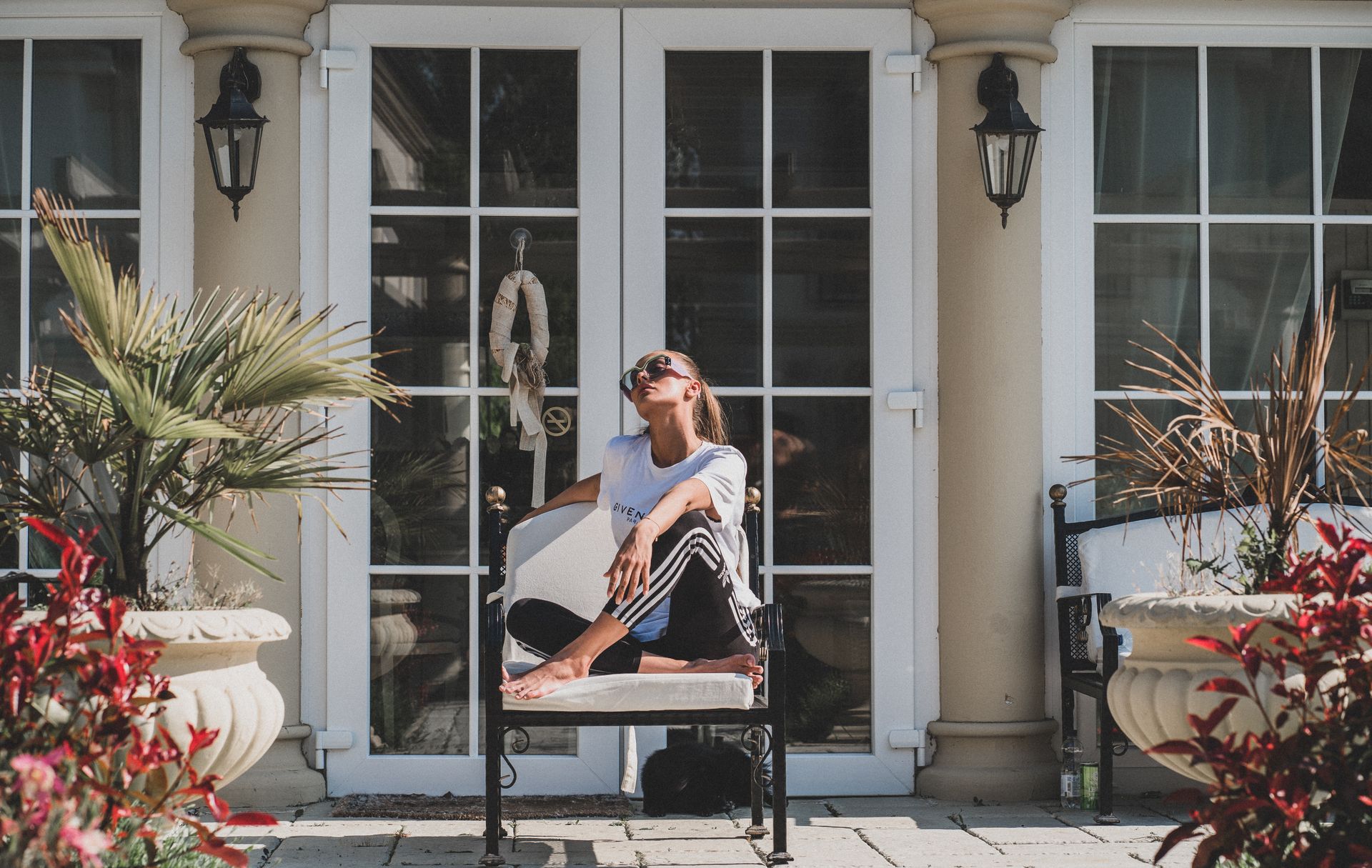 Woman enjoying a sunny day on a modern porch surrounded by stylish garden décor.