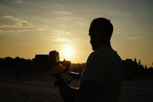 Foto Da Silhueta De Um Homem Segurando Uma Câmera Durante A Hora Dourada