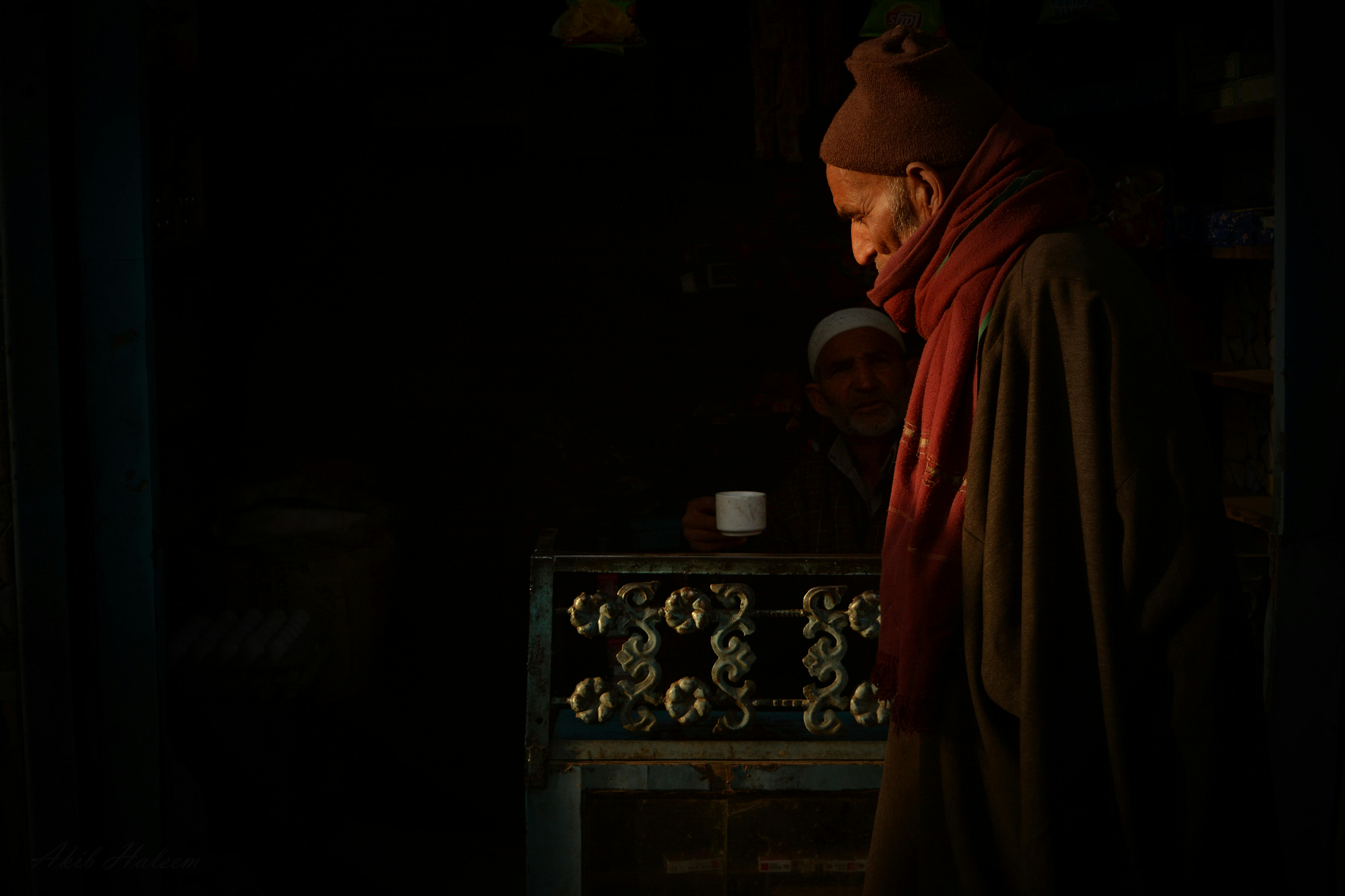 man standing near man sitting while holding mug