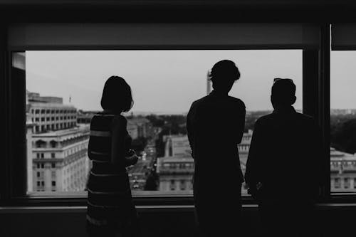 Free Blurry silhouette of Three people Looking Through the window  in the black and white night
 Stock Photo