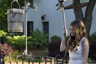 一位穿着白色连衣裙的年轻女子，在乡村井旁若有所思