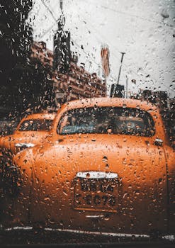 透过雨水覆盖的窗户，可以看到加尔各答街道上一辆橙色出租车