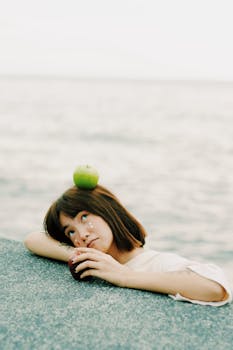 一个女人躺在海边沉思，头上顶着一个青苹果