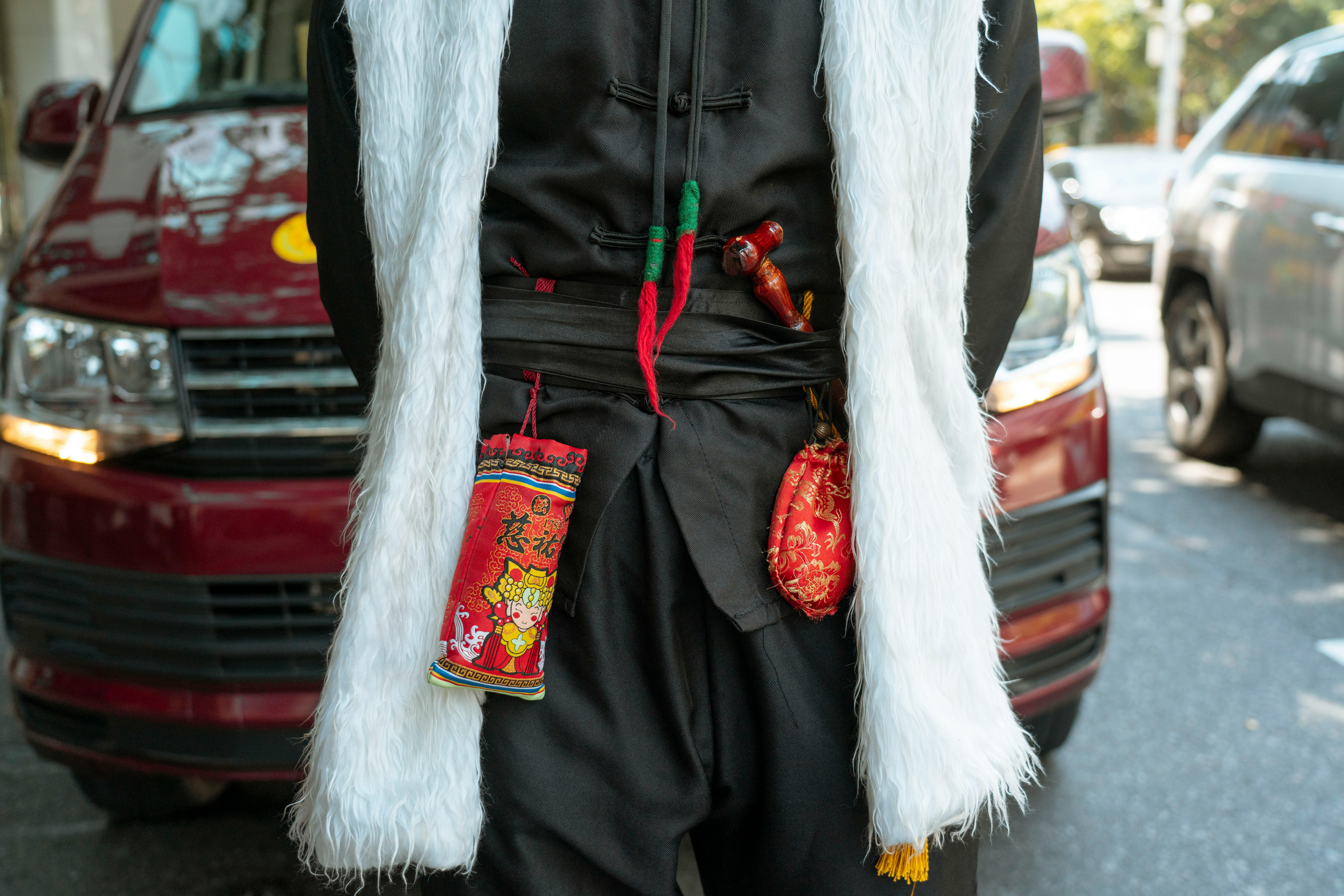 Close-up of traditional outfit with lucky charms in a bustling city street.