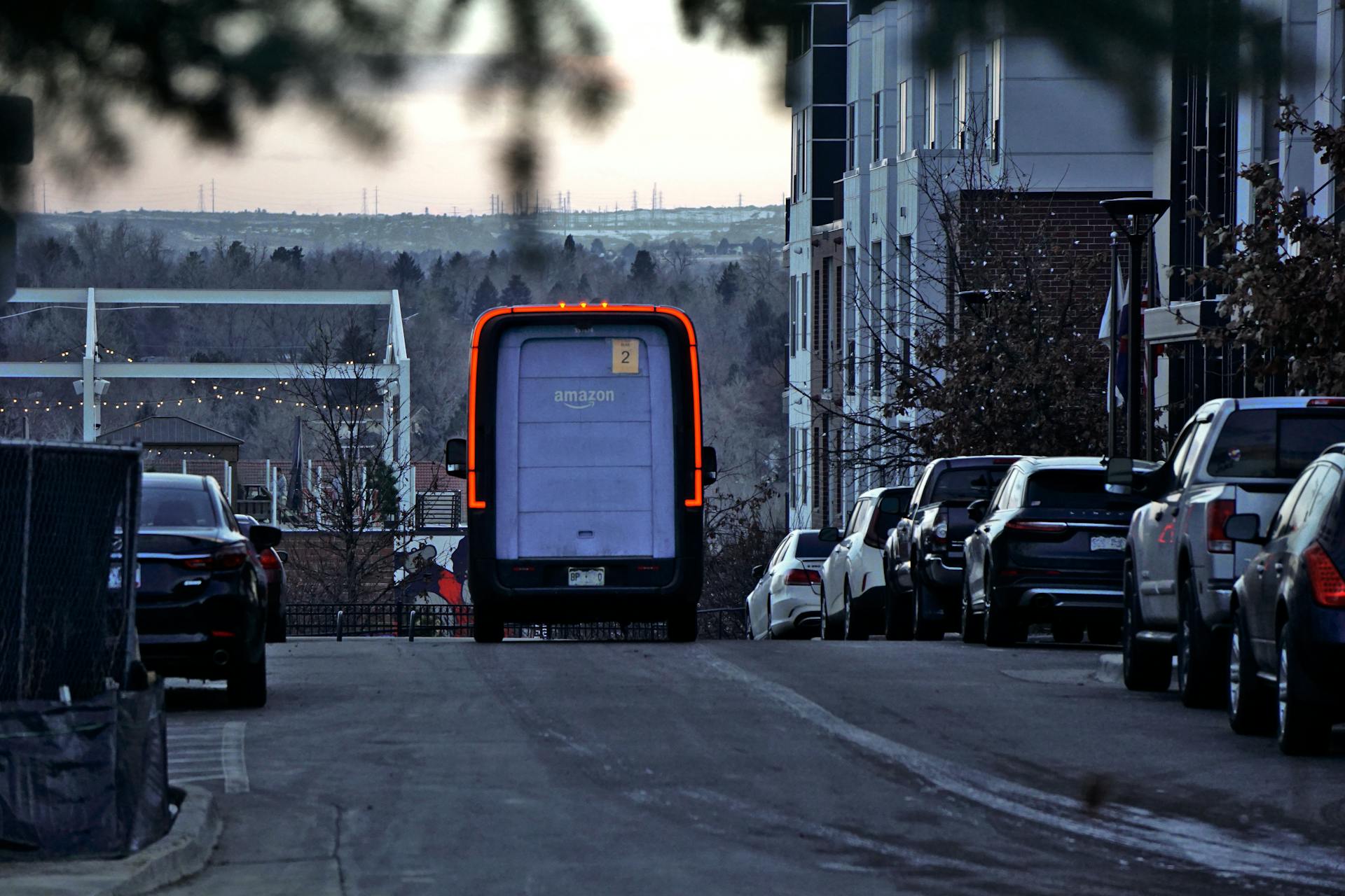 A truck is driving down a street with cars parked on the side