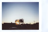 房屋和树木的剪影映衬着秀丽的日落，营造出宁静祥和的氛围