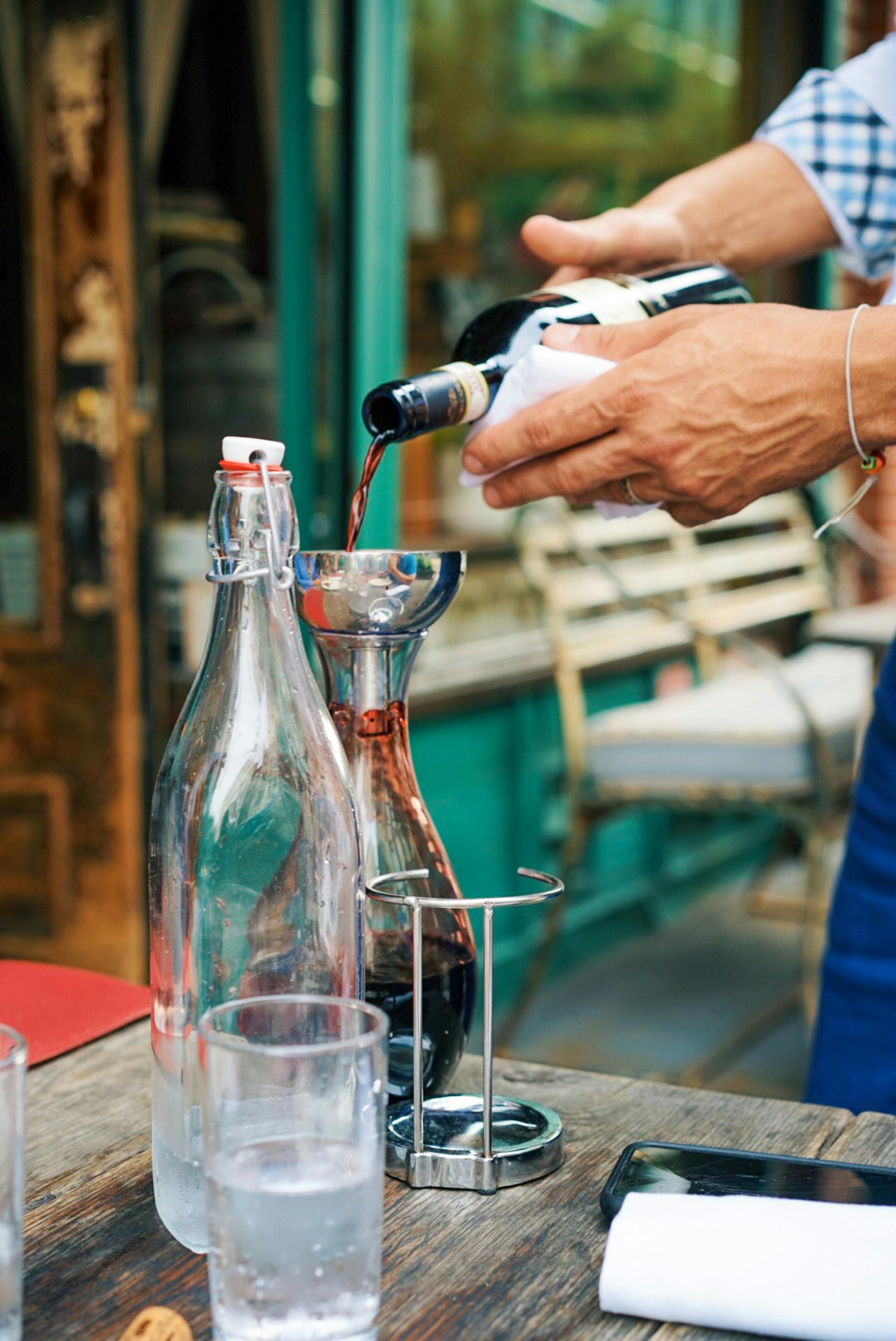 Person Pouring Wine on a Clear Glass Bottle · Free Stock Photo