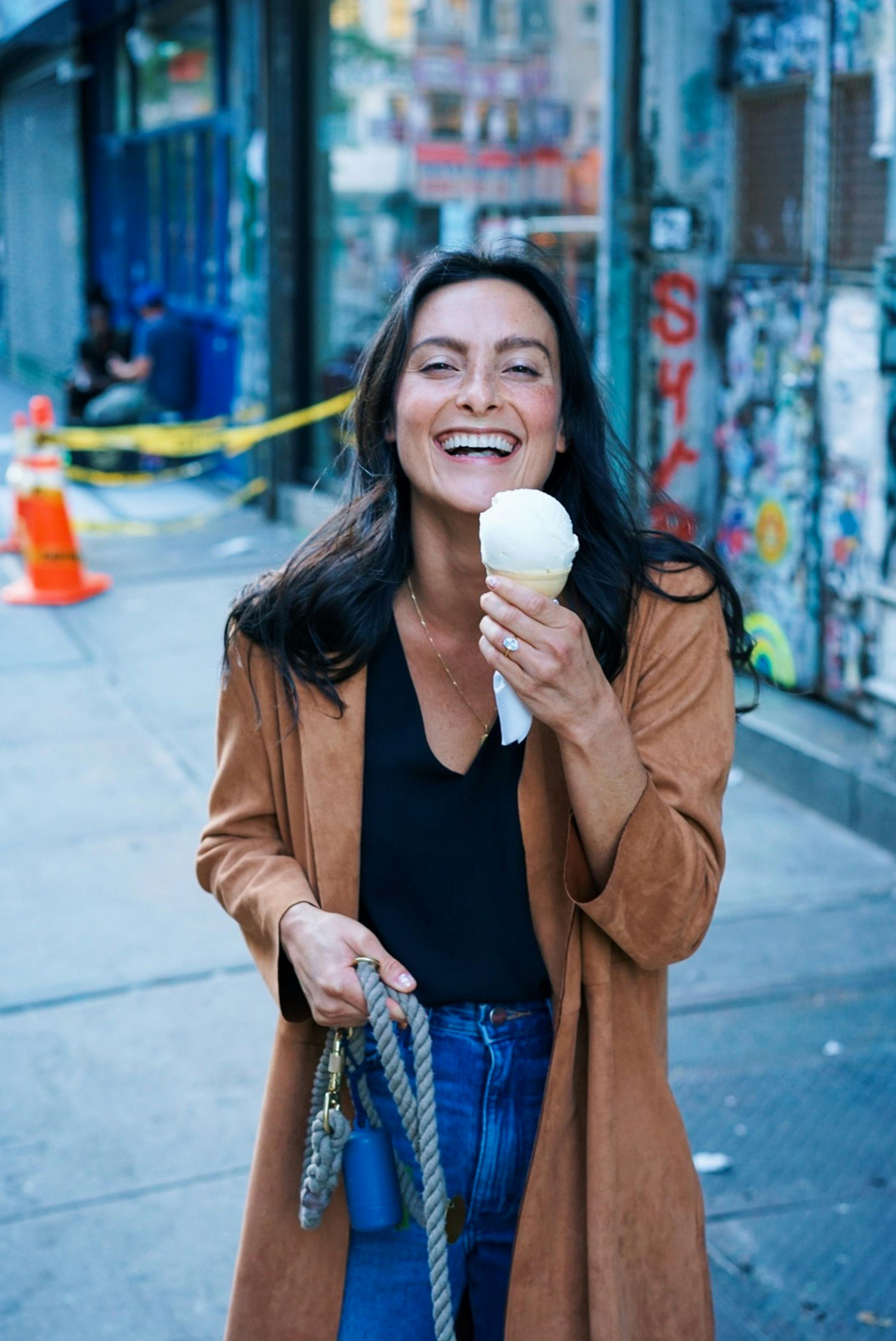 woman wearing brown trench coat while holding ice cream