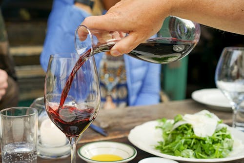 Free Person Pouring Red Wine on Wine Glass Stock Photo