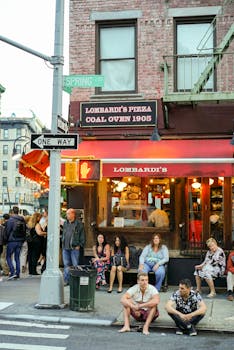 People gather outside Lombardi's Pizza on a busy street in New York City.