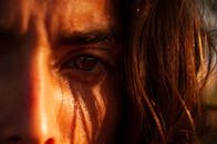 特写镜头中，一个人的眼睛部分被头发覆盖，光线自然且富有戏剧性