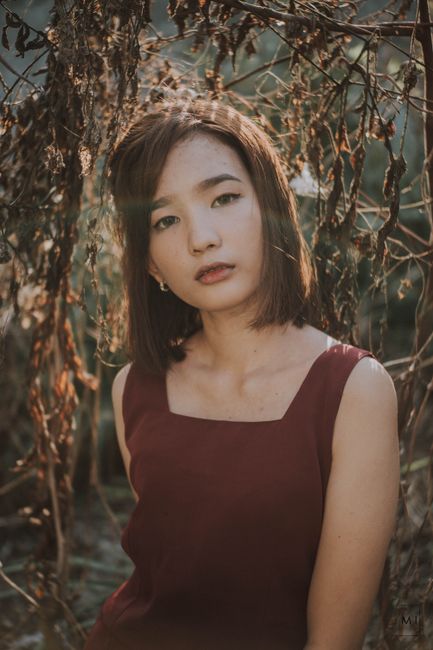 Portrait of a young woman in a natural setting with soft lighting.