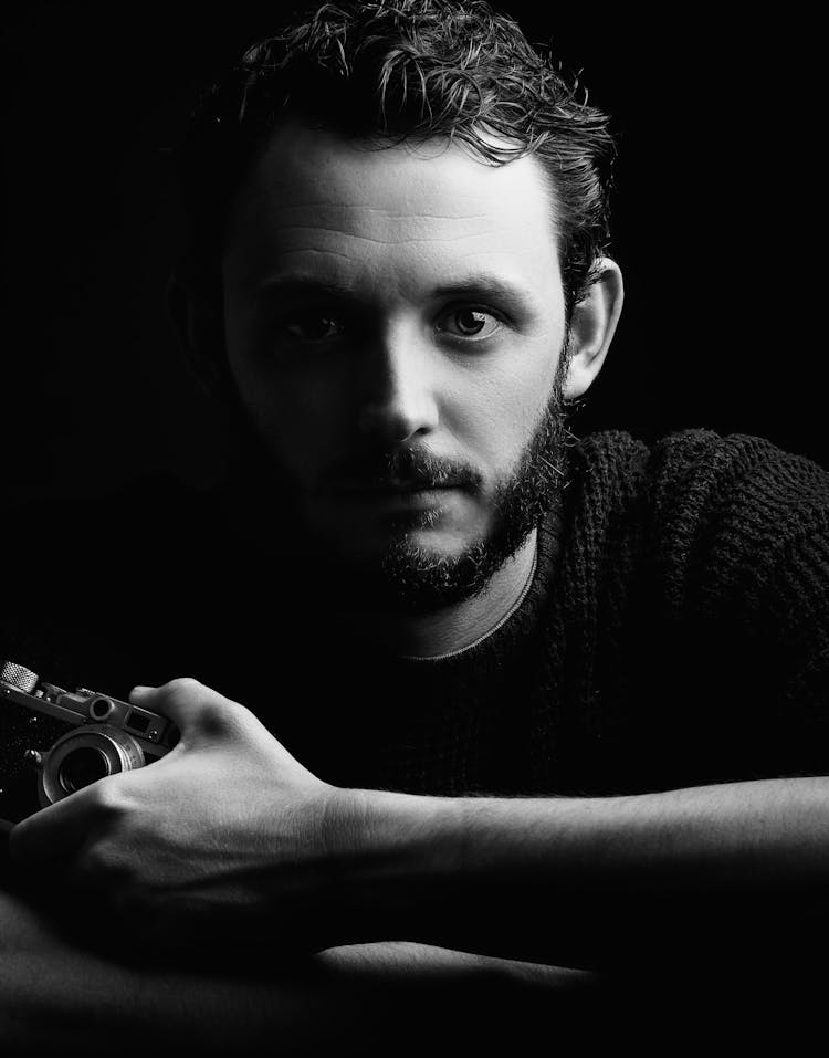 Grayscale Portrait Photo Of Man Wearing Holding A Camera