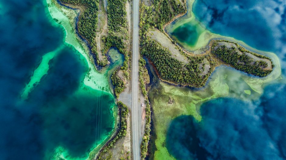 Stunning aerial view of a tropical island surrounded by turquoise and blue waters, showcasing nature's beauty.