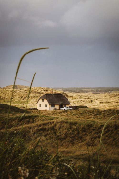 Free Picturesque rural landscape with a single house in Denmark under a cloudy sky. Stock Photo