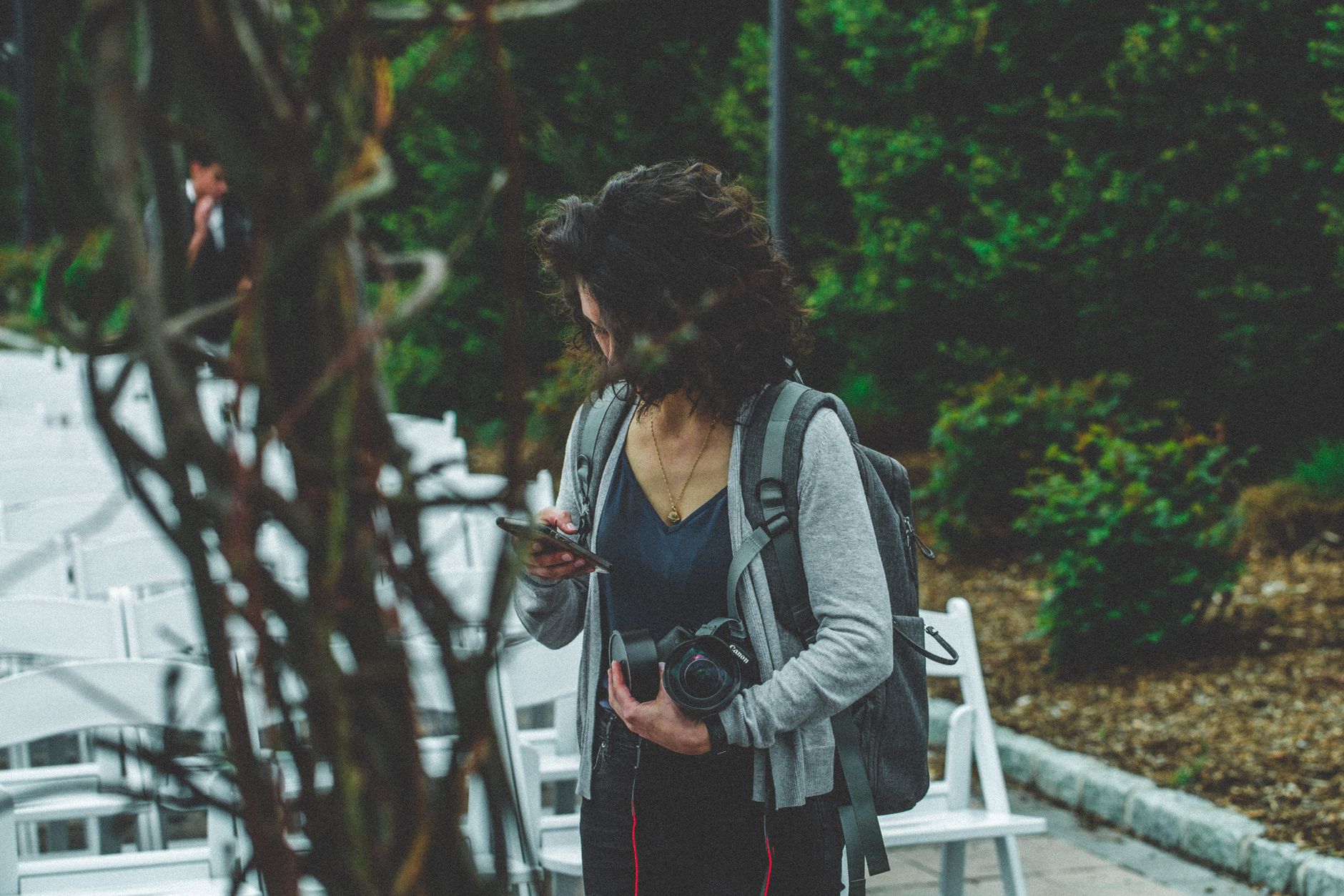 Best Phone for Photographers as a Second Camera (A Practical Guide) Woman photographer with camera and cellphone among chairs in an outdoor setting