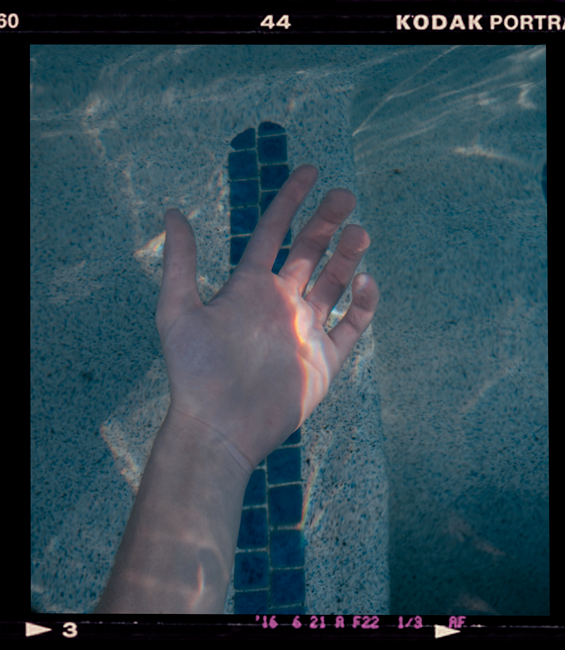 A serene underwater shot featuring a hand in natural sunlight, framed by Kodak film edges.