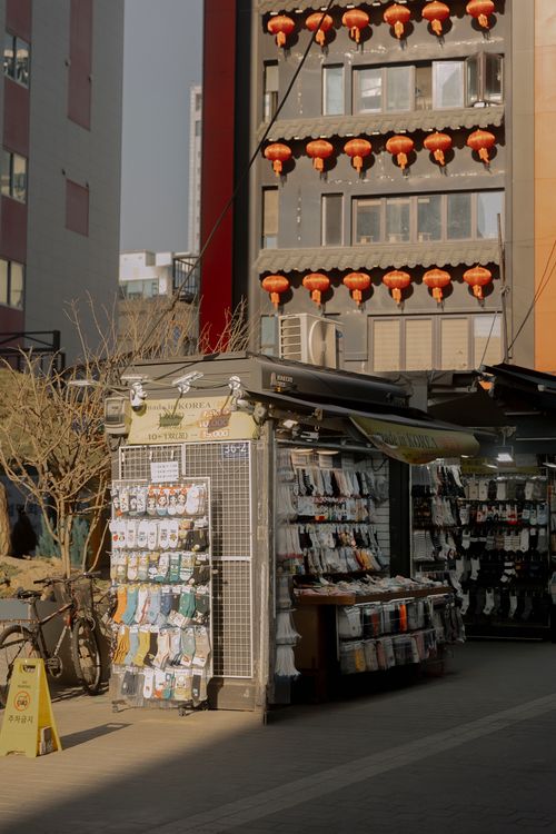 Free A vibrant city street featuring a sock kiosk, lanterns, and urban architecture, highlighting small business charm. Stock Photo