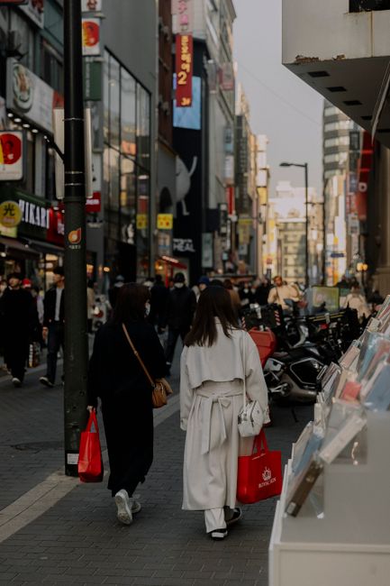 Fotomural Personas caminando en una calle concurrida de la ciudad, mostrando la vida urbana con arquitectura moderna.