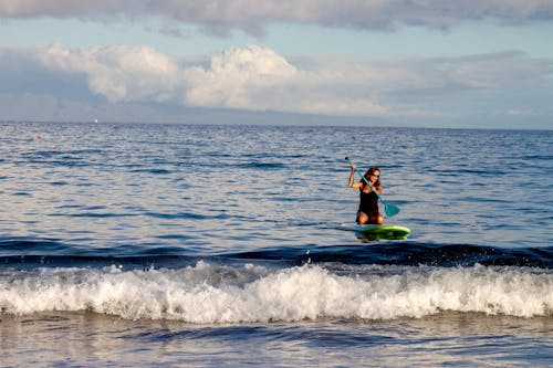 Mujer Montando Tabla De Surf Verde Con Paleta