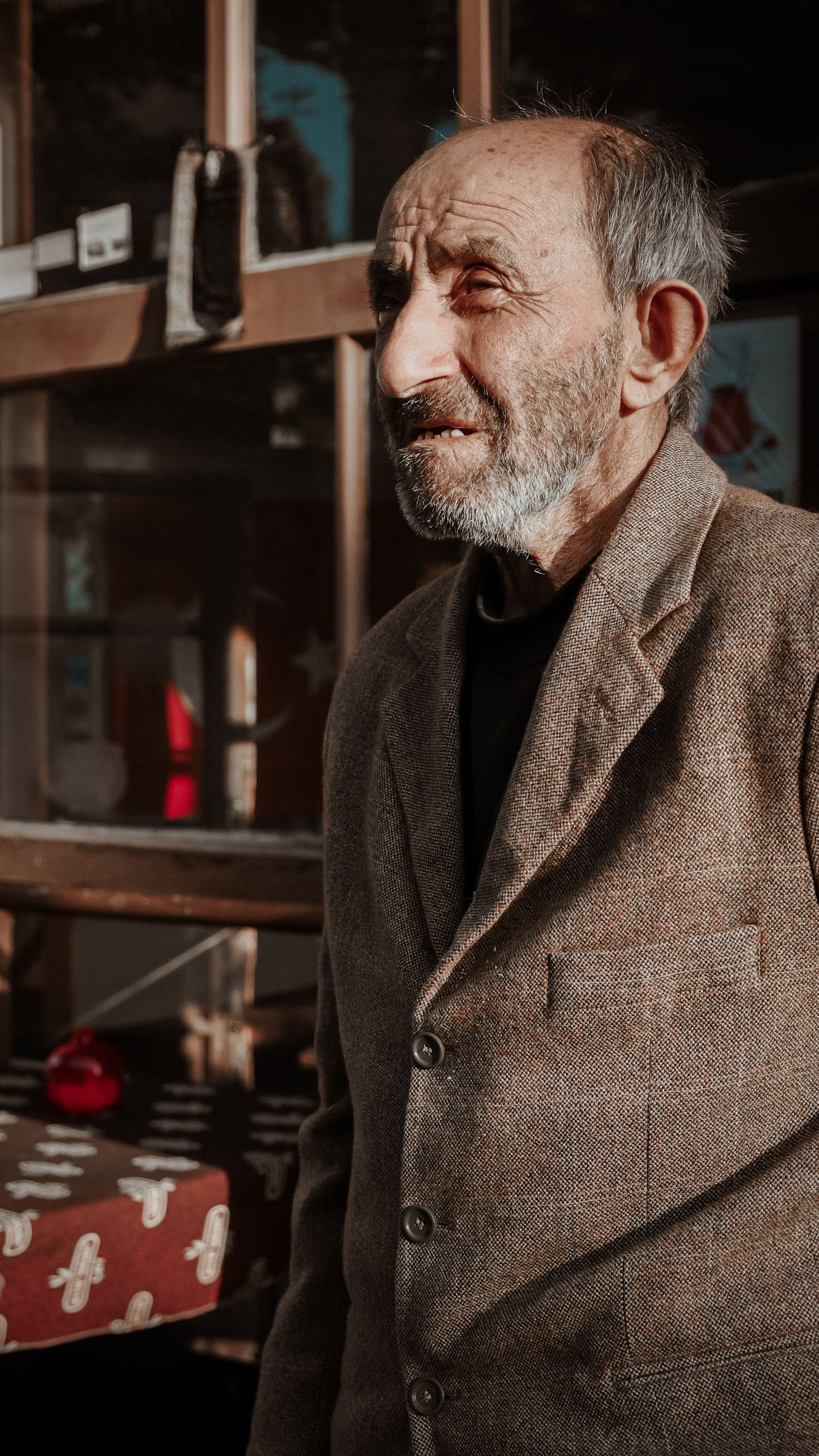 Elderly man with facial hair in a blazer standing outdoors during daylight. Captured in a vintage style.
